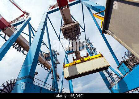 Ein massive Fracht Kran transportiert einen Container von einem LKW auf einem Frachter Schiff in einem Hafen Dock. Stockfoto