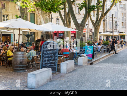 Menschen Essen im Restaurant im Freien Tische in den frühen Abendstunden am Place des Corps Saints, Avignon, Frankreich Stockfoto