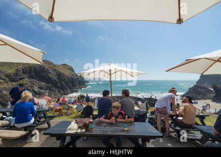 Menschen Essen und trinken auf der Terrasse des Cornwall Kynance Cove Cafe mit Panorama Beache und Türkis Meer Stockfoto