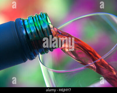 Alfresco Rotwein Gießen von schraubverschluss Flasche in ein Glas Wein mit Garten Blumen im Hintergrund Stockfoto