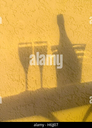 Schatten-Silhouette des prickelnden Champagner Flasche Wein, Eiskübel und zwei Gläser auf Tisch im freien Terrasse bei Sonnenuntergang Stockfoto