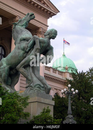Statue-Denkmal von Mensch und Pferd Eintrag Haus der nationalen Versammlung von Serbien Parlamentsgebäude mit Nationalflagge Belgra Stockfoto