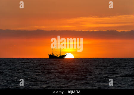 Piraten Schiff Meer Sonnenuntergang Silhouette ist eine alte hölzerne Piratenschiff mit voller Fahnen beim Sonnenuntergang am Meer Horizont in einer Farbe Stockfoto