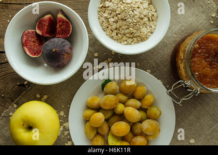 Feigen, Pflaumen, Haferflocken und Apple auf Leinen Stockfoto