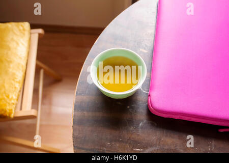 Grüner Tee und Apple Mac Air Book in rosa Hülle auf dem runden Tisch Stockfoto