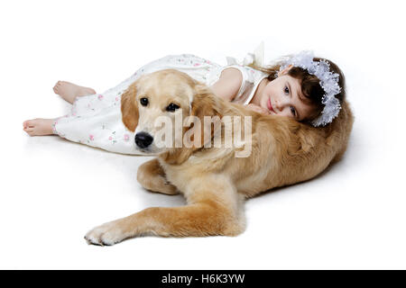 Kleines Mädchen auf golden Retriever Welpe liegend Stockfoto