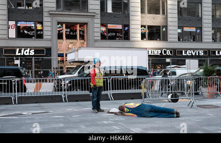 Bauarbeiter ziehen von Kabeln durch einen Bürgersteig-Kanal im Zentrum von New York City zu sehen. Stockfoto