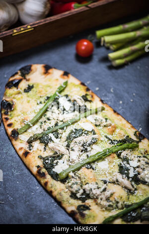 grünen Spargel und Hähnchen Pizza auf Holz befeuerten dünne Kruste Stockfoto