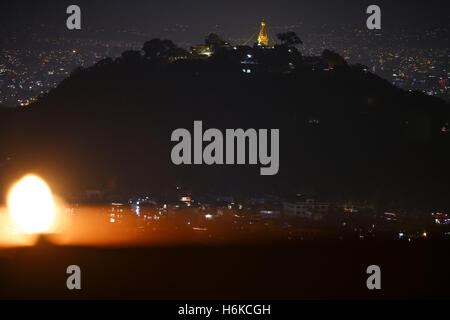 Kathmandu, Nepal. 30. Oktober 2016. Eine Öllampe leuchtet auf einer Terrasse als Swayambhunath Stupa, ein UNESCO-Weltkulturerbe, gesehen auf einem Hügel am dritten Tag der zweitgrößte Fünftage-religiöses Fest Tihar aufleuchtet oder Diwali, das Lichterfest in Kathmandu, Nepal auf Sonntag, 30. Oktober 2016 genannt. An jedem Tag während des fünftägigen Festivals verehren Anhänger Krähen, Hunde und Kühe, die eine mütterliche Figur bedeutet die Beziehung zwischen Mensch, Gottheit und Tiere gelten. Anhänger verehren auch Göttin des Reichtums Laxmi beleuchten und dekorieren ihre hom Stockfoto