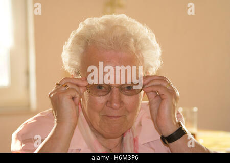 Oma aufsetzt ihre Brille Stockfoto