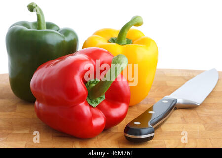 Rote, gelbe und grüne Paprika auf Schneidebrett. Mit Messer. Stockfoto