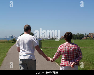 Applying paar hand in hand gehen an Weston Shore Strandpromenade in Richtung Woolston, Southampton, Hampshire, UK Stockfoto