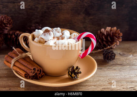 Heiße Schokolade mit Marshmallows, Zimt und Pfefferminze candy Cane über rustikalen Tisch close up - hausgemachte festliches Heißgetränk Stockfoto