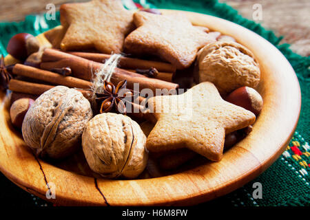Rustikale Weihnachts-Dekoration mit Lebkuchen, Nüssen und weihnachtlichen Gewürzen auf Holzplatte hautnah Stockfoto