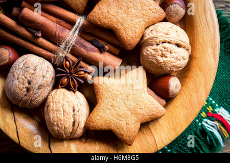 Rustikale Weihnachts-Dekoration mit Lebkuchen, Nüssen und weihnachtlichen Gewürzen über Holzplatte Stockfoto