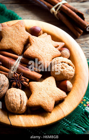 Rustikale Weihnachts-Dekoration mit Lebkuchen, Nüssen und weihnachtlichen Gewürzen auf Holzplatte hautnah Stockfoto