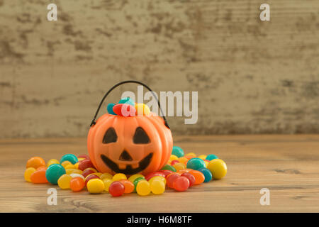 Halloween Kürbis Korb voller Süßigkeiten auf einem hölzernen Hintergrund Stockfoto