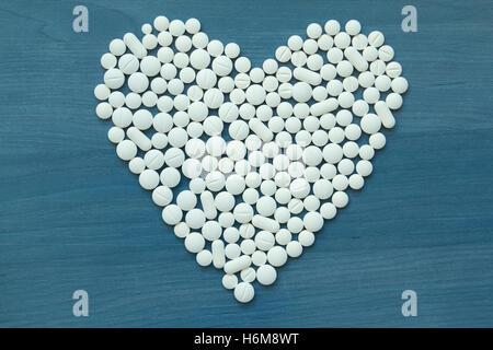 Bild von Herz aus weißen Tabletten auf blauem Hintergrund Stockfoto