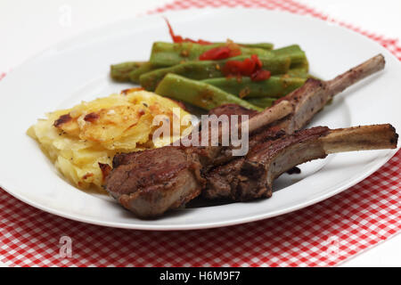 Lammkoteletts mit Kartoffelgratin und grünen Bohnen Stockfoto