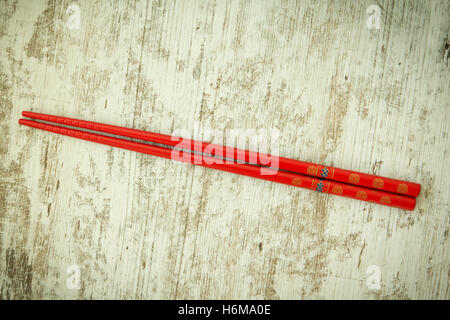 Orientalische Stäbchen in rot auf einem hölzernen Hintergrund Stockfoto