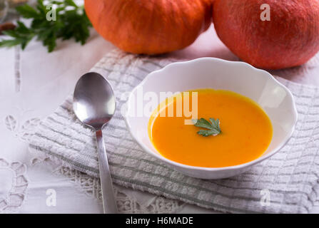 Hokkaido-Kürbissuppe auf weiße Tischdecke mit zwei Kürbisse hinter. Stockfoto