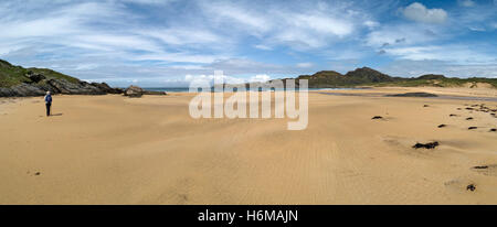 Einsame Gestalt zu Fuß am leeren Sandstrand von Kiloran Bay Beach auf der abgelegenen Hebriden Insel Colonsay, Schottland, UK. Stockfoto