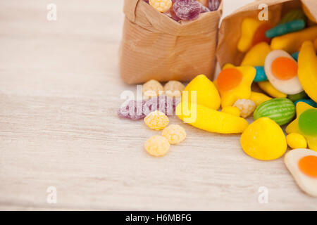 Papiertaschen gefüllt mit Süßigkeiten auf einem grauen Hintergrund aus Holz Stockfoto