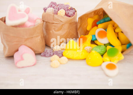 Papiertaschen gefüllt mit Süßigkeiten auf einem grauen Hintergrund aus Holz Stockfoto