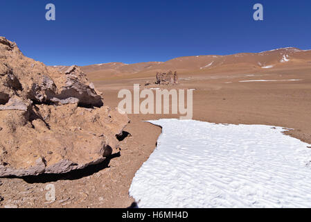 Erosion geformte Felsen in der Wüste neben einem Eisblock. Stockfoto