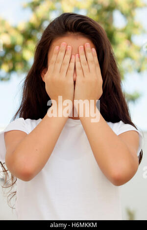 Teenager-Mädchen mit zwölf Jahren bedeckte ihr Gesicht mit den Händen Stockfoto