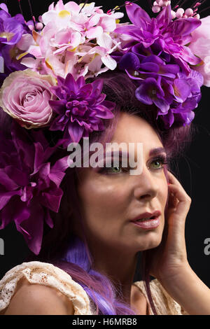 Modell Frau mit architektonischen floral lila Haarteil tragen weiße Spitzen Kleid Fotoshooting vor schwarzen Studio-Hintergrund Stockfoto