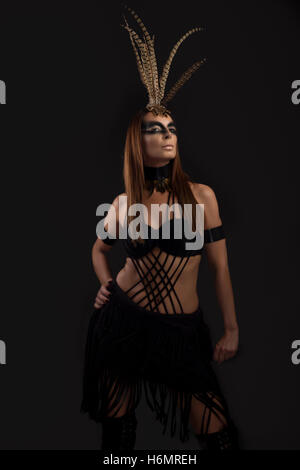 Gebräunte weibliches Modell in Amazonas Superhelden-Style-Outfit mit Feder Kopfschmuck Stockfoto