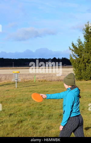 Junge Frau wirft CD zum Ziel auf Disc-Golf-Kurs. Stockfoto