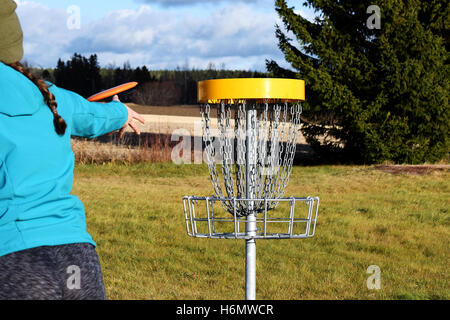 Junge Frau wirft CD zum Ziel auf Disc-Golf-Kurs. Stockfoto