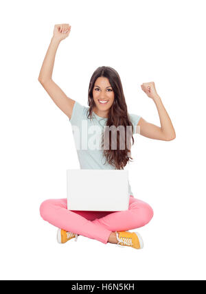 Gewinner-Mädchen sitzen auf dem Boden mit einem Laptop isoliert auf weißem Hintergrund Stockfoto