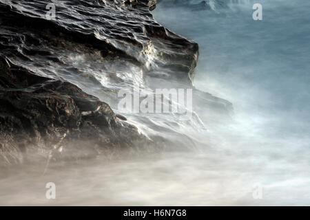 Wellen brechen sich am Felsen Stockfoto