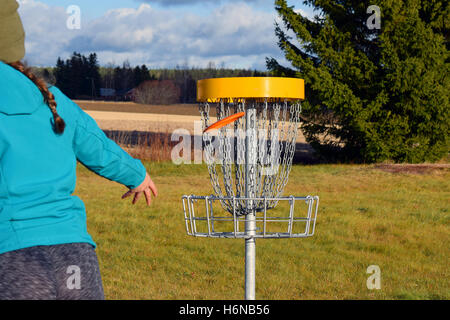 Junge Frau wirft CD zum Ziel auf Disc-Golf-Kurs. Stockfoto