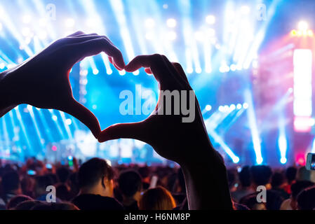 Silhouette eines Herzens geformte Hände und Masse des Publikums auf live-Konzert Stockfoto