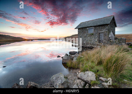 Sonnenuntergang über einer alten steinernen Bootshaus am Ufer des Devoke Wasser, einen abgelegenen See auf Birker fiel in den Lake District national par Stockfoto