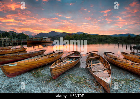 Atemberaubenden Sonnenuntergang über hölzerne Ruderboote auf Derwentwater in Keswick im Lake District Nationla Park in Cumbria Stockfoto