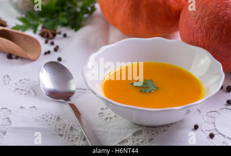 Hokkaido-Kürbissuppe auf weiße Tischdecke mit ganzen Kürbis hinter. Stockfoto