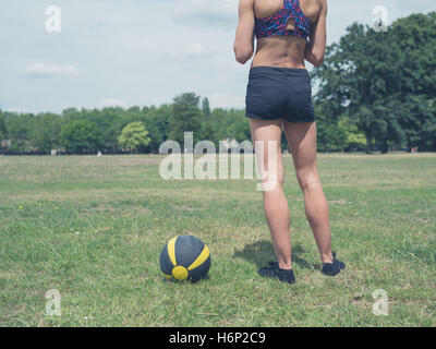 Vintage getönten Schuss eines Anfalls und sportliche Frau steht an einem sonnigen Sommertag im Park mit einem Medizinball Stockfoto