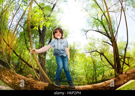 Fröhlicher Junge Spaß auf den umgestürzten Baum stehend Stockfoto