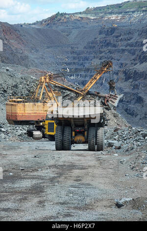 Schwere Muldenkipper verladen mit Eisenerz auf den Tagebau durch den Bagger Stockfoto
