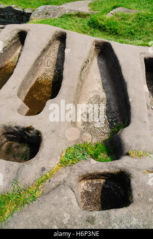 Zwei der sechs Körperangepasster Gräber & zwei Kreuz-Buchsen geschnitten in einem Sandstein Felsen neben St Patricks C8th angelsächsischen Kapelle auf Heysham Barrows. Stockfoto