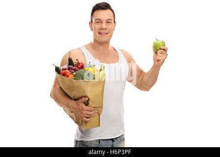 Junger Mann hält eine Einkaufstasche voller Obst und Gemüse und ein Apfel isoliert auf weißem Hintergrund Stockfoto