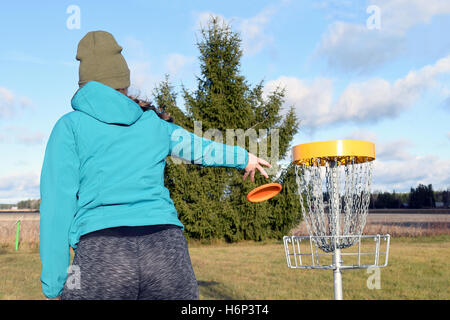 Junge Frau wirft CD zum Ziel auf Disc-Golf-Kurs. Stockfoto