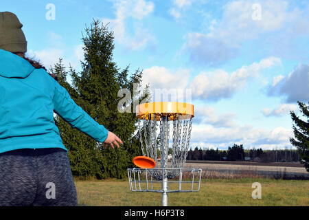 Junge Frau wirft CD zum Ziel auf Disc-Golf-Kurs. Stockfoto