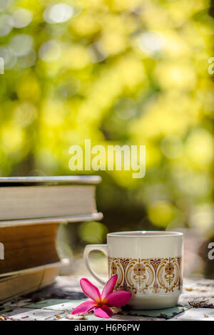 Tasse Kaffee mit Blume Schreibtisch, soft-Fokus-Hintergrund-Unschärfe-Buch Stockfoto