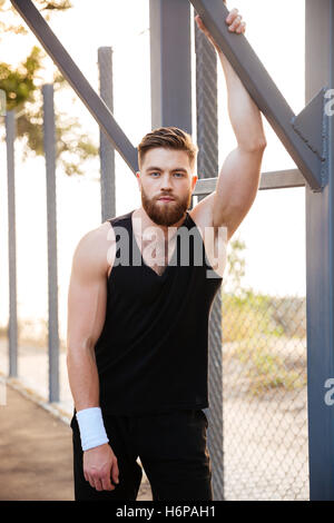 Handsome bärtiger junger Sportler in Sportbekleidung und Armband stehen im freien Stockfoto